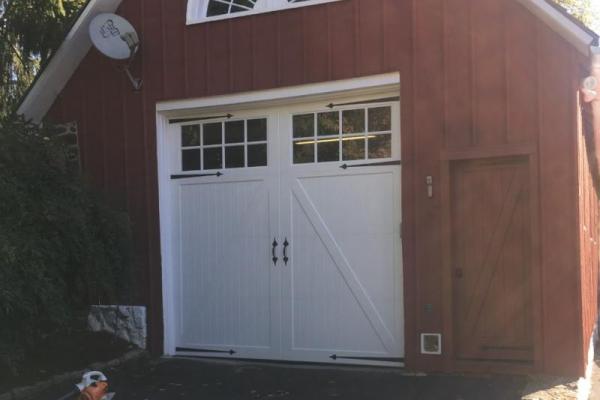 An extra tall carriage house overlay style door on a red barn/garage.