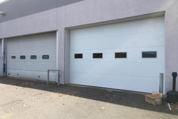 A newly installed commercial ribbed steel door next to the previous door.