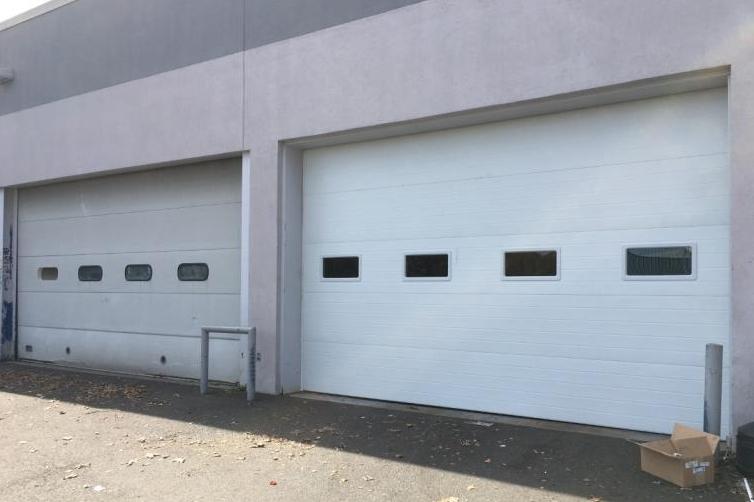 A newly installed commercial ribbed steel door next to the previous door.